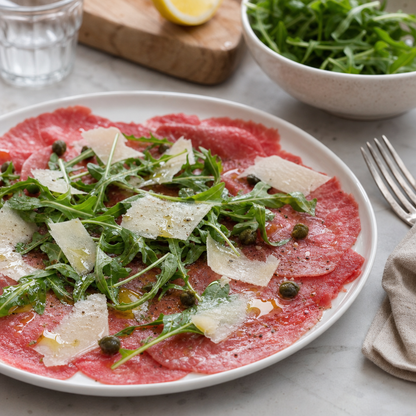Carpaccio van Angus op een wit bord met rucola, Parmezaan en kappertjes