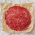 Dun gesneden Angus carpaccio op bruin papier, bovenaanzicht