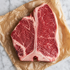Rauwe T-bone steak van Angus op bakpapier met zichtbaar T-vormig bot en marmering