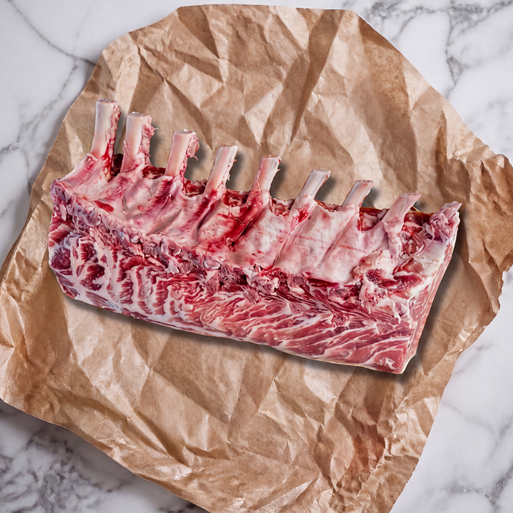 Rauw Iberico rack met gefrenchde botjes op bakpapier, klaar voor BBQ of oven
