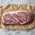 Rauwe Iberico rugfilet op bruin papier, met fijne vetmarmering en een gelijkmatige, dikke snit