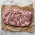Rauw Iberico secreto met fijne vetdooradering op bruin papier