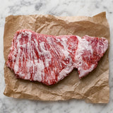Rauw Iberico secreto met fijne vetdooradering op bruin papier