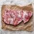 Rauw Iberico secreto met fijne vetdooradering op bruin papier