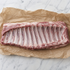 Rauwe Iberico spareribs op bakpapier, met zichtbare ribben en vetdooradering