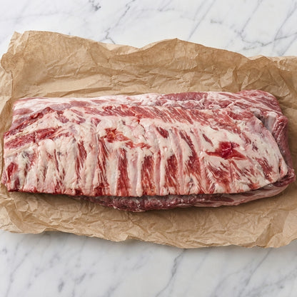 Rauwe Iberico spareribs op bakpapier, met zichtbare ribben en vetdooradering