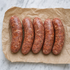 Vijf rauwe jalapeño BBQ worsten op bakpapier, klaar voor de grill