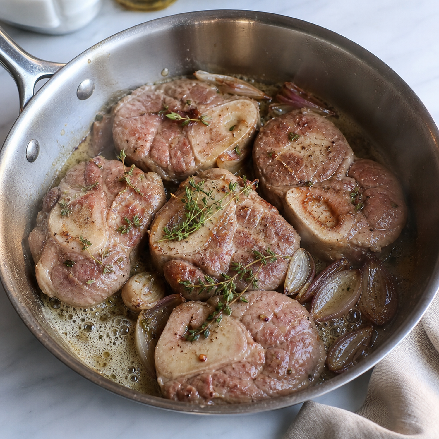 Kalfs ossobuco schijven bruin aan het garen in een pan met sjalot en tijm