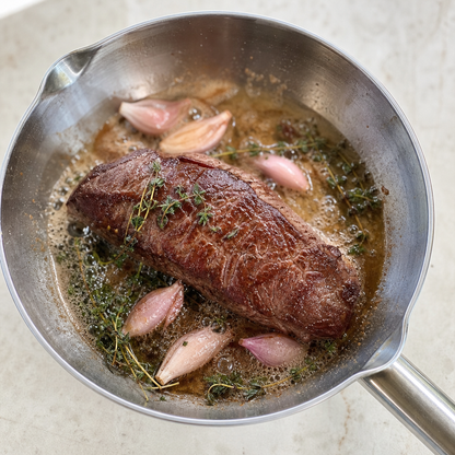 Aangebraden ossenhaas in pan met sjalot, knoflook en kruiden