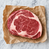 Rauwe rib-eye steak met marmering op bruin papier, van boven gezien