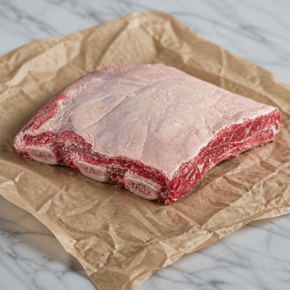 Rauwe Schotse short rib met bot, op bruin papier op een licht marmeren ondergrond
