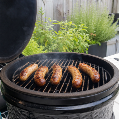 Vijf varkenssaucijzen op de barbecue, licht gebruind en grillend boven het rooster
