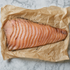 Heel stuk gerookte zalm, voor in plakken gesneden, op bruin papier