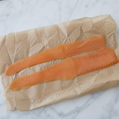 Twee lange plakken gerookte zalm op bruin papier