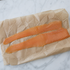 Twee lange plakken gerookte zalm op bruin papier